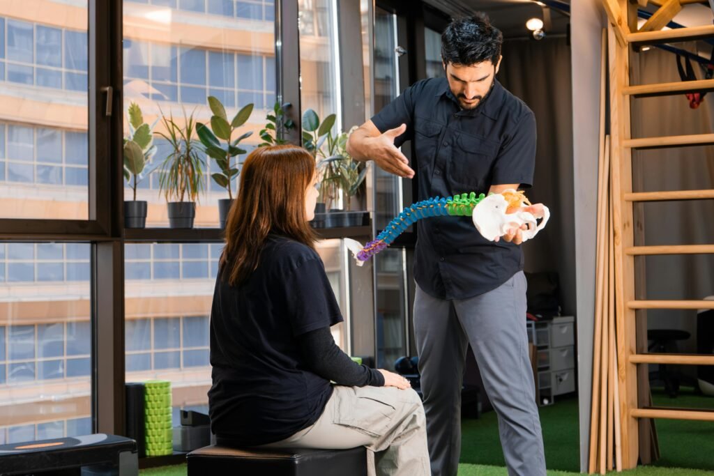 Physiotherapist using a spine model to explain a clinical treatment plan to a patient