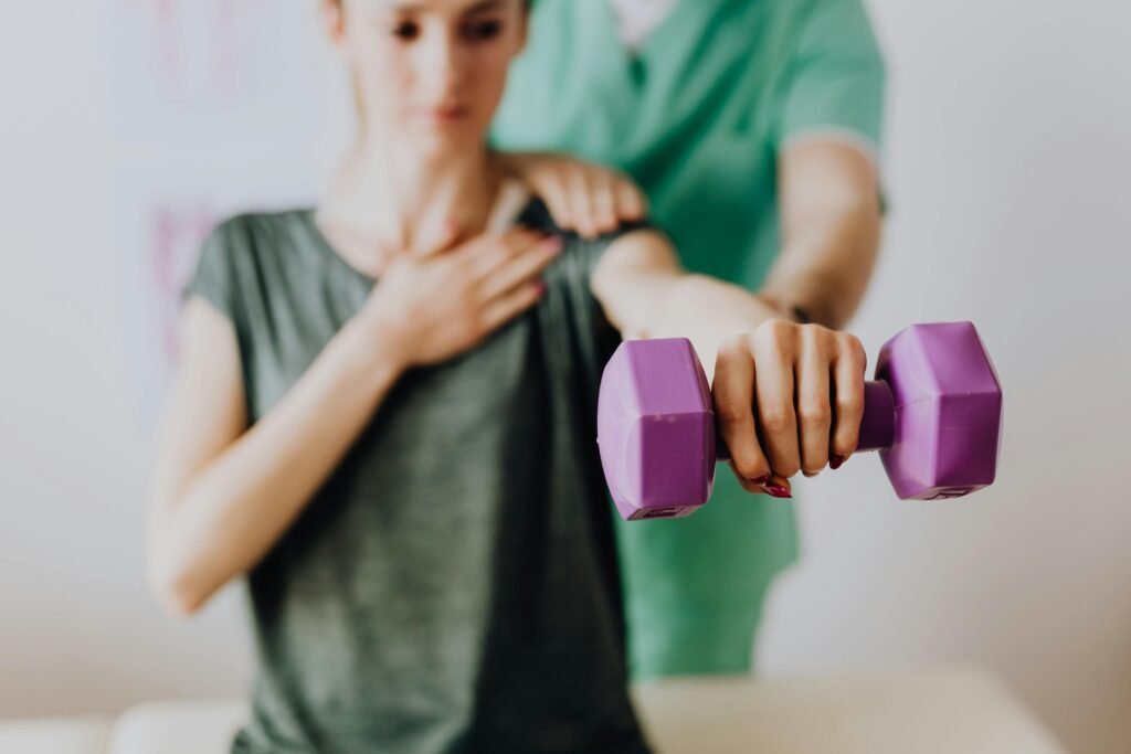 Professional physiotherapist guiding a patient through a shoulder rehabilitation exercise with a dumbbell