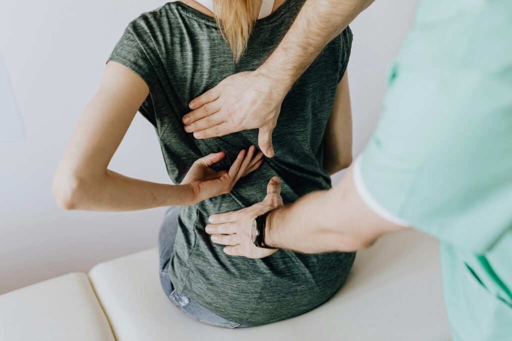 Physiotherapist performing a manual spine palpation and chiropractic assessment on a patient experiencing lower back pain.