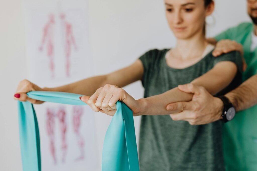 Physical therapist guiding a female patient through upper body resistance band exercises during a neurological rehabilitation session.