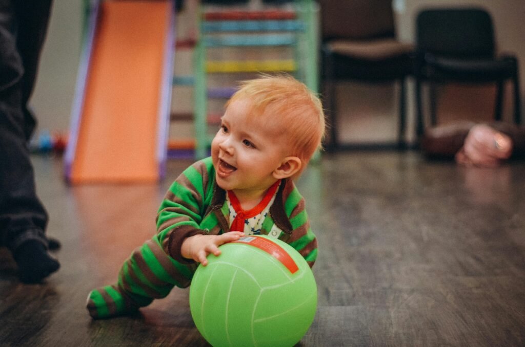 Pediatric physical therapist helping a young child with developmental delays improve motor skills and balance using a therapy ball.